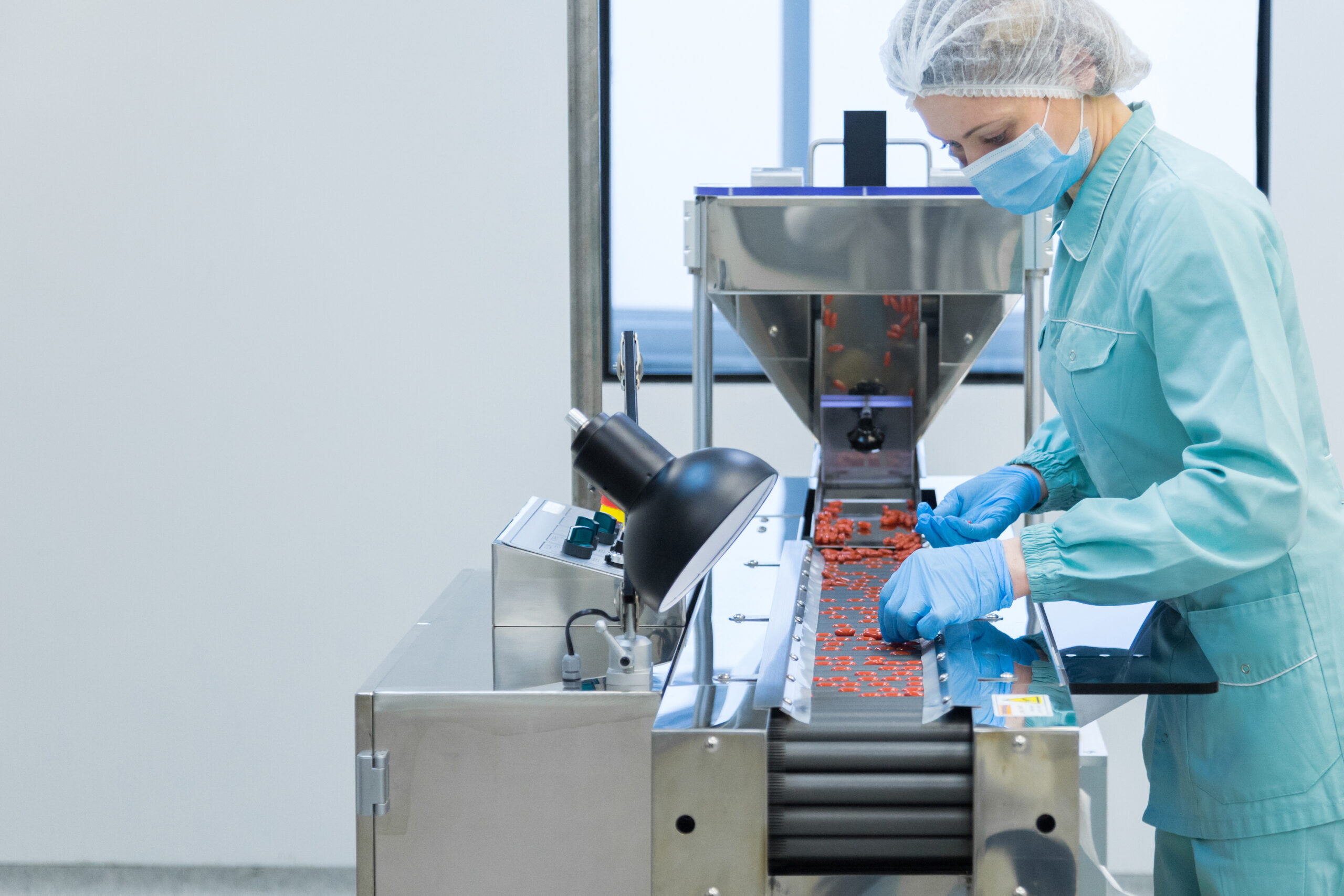 Pharmaceutical technician in sterile environment working on production of pills at pharmacy factory